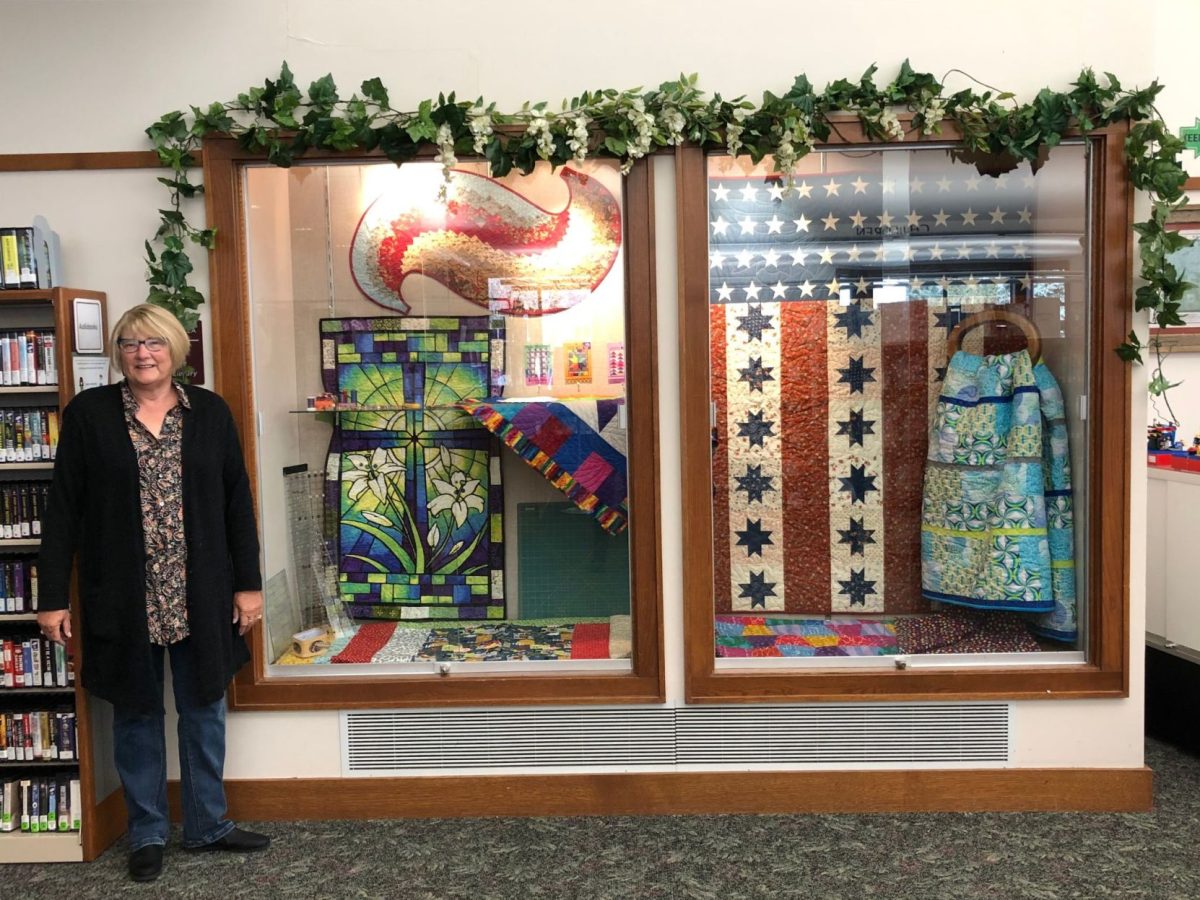 <p>Lori Lacina is pictured with quilts and notions from the Fabriholics group.</p>