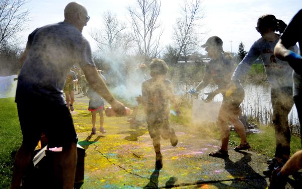 Participants in the 2022 Spartan Dash undergo “Spartan Decontamination” or “Do or Dye” as volunteers blast them with colored chalk dust.