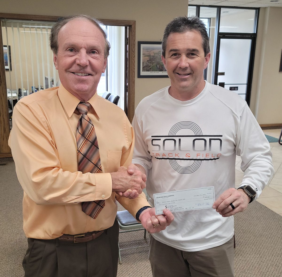 <p>Solon Beef Days Treasurer Don Ellis presents a $400 check to girls head track coach Brent Sands.</p>