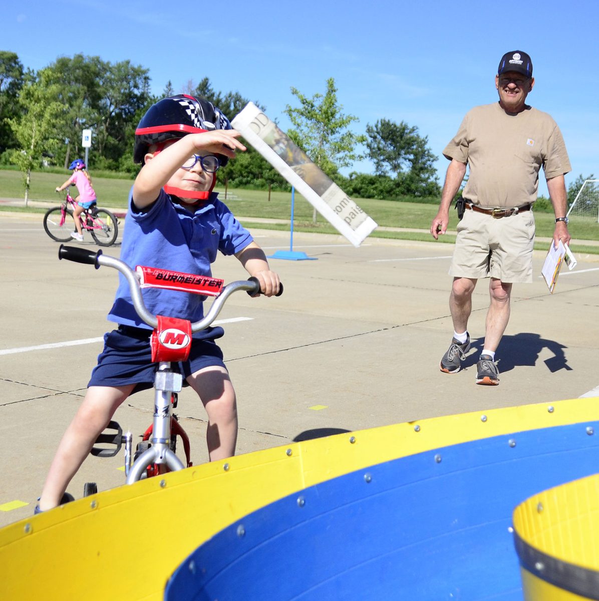 Isaac Early tosses a newspaper into the target during the Solon Optimist Club&#8217;s annual bike rodeo Saturday, June 18 at the middle school. Early, age 3, didn&#8217;t quite understand the rules, but had fun nonetheless, to Optimist Club member Donnie Miller&#8217;s amusement.