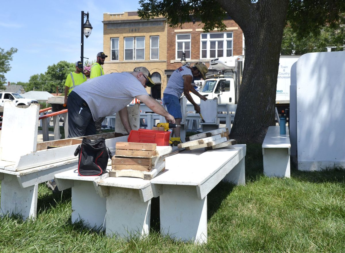 Cliff Maier and Glen Erenberger assemble benches while a pair of city public works employees move on to their next task while assisting in the set up for the 2022 Solon Beef Days.