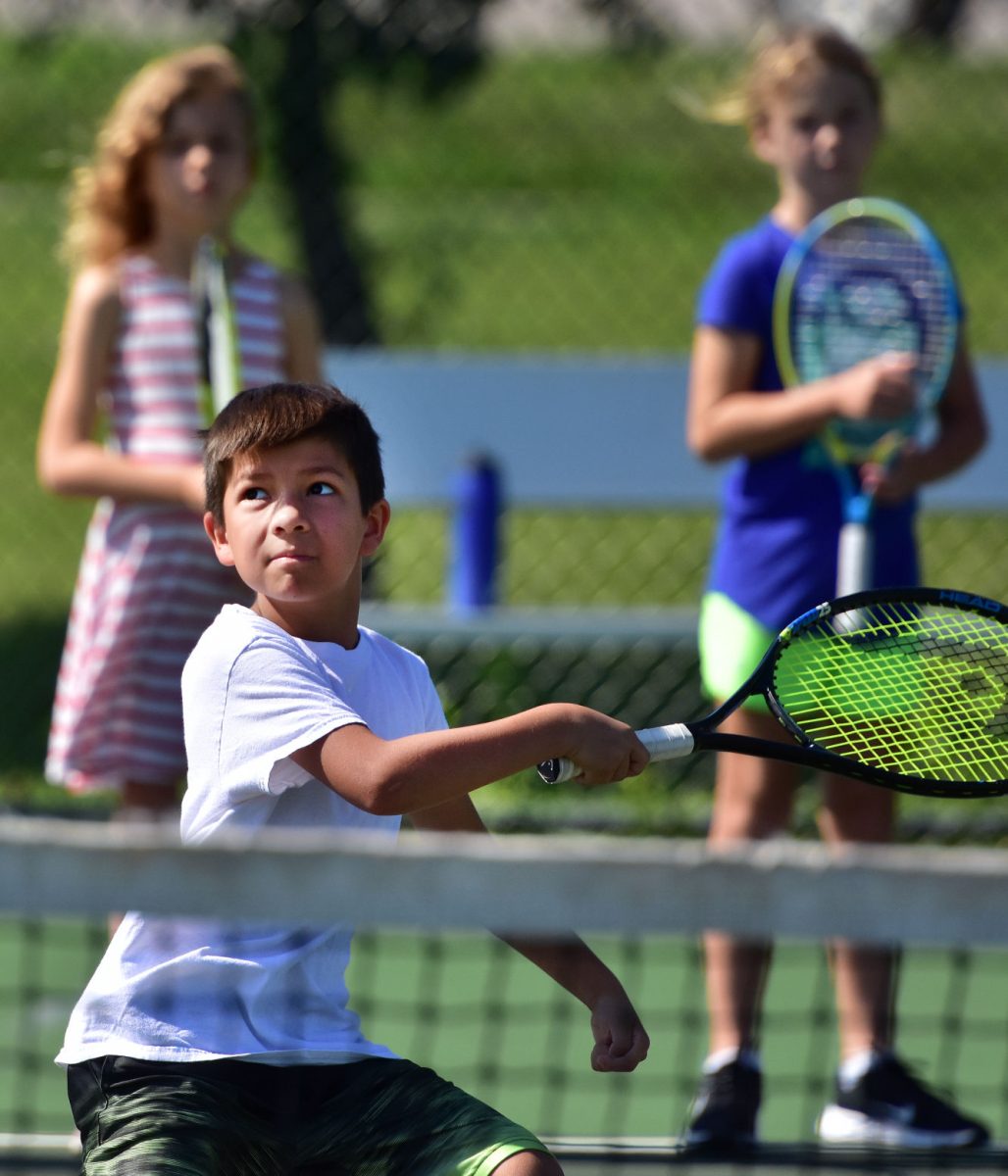 <p>Cai Brock watches the ball after successfully swatting it with the racket Wednesday, July 20 on the final day of the Solon Recreation Department’s tennis camp.</p>