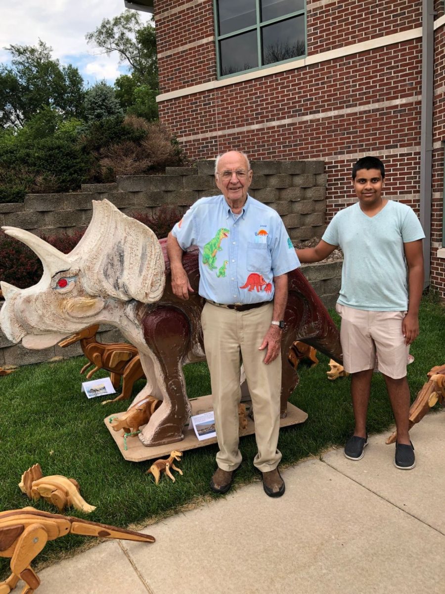 Jack Neuzil (left) with Krishna Bharadwaj (right) and many of the dinosaurs made by Neuzil on display at the Solon Public Library.