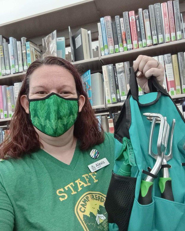 Adult Services Librarian, Alexis, shows off the garden tools available for check-out from the Library of Things collection.