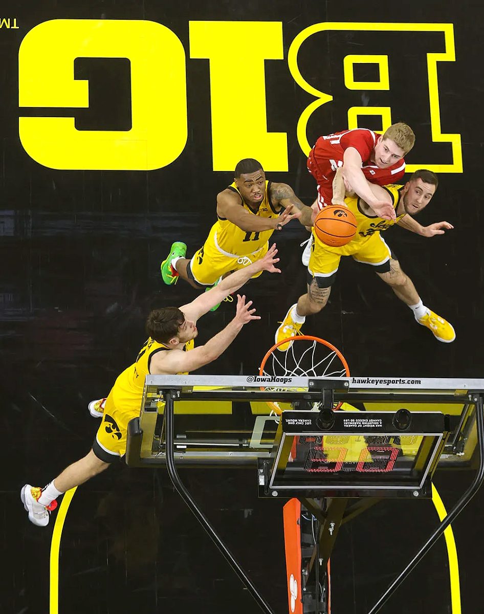 Filip Rebraca, Tony Perkins, and Connor McCaffery battle for a rebound during the first half of their game at Carver-Hawkeye Arena in Iowa City Sunday, Dec. 11.