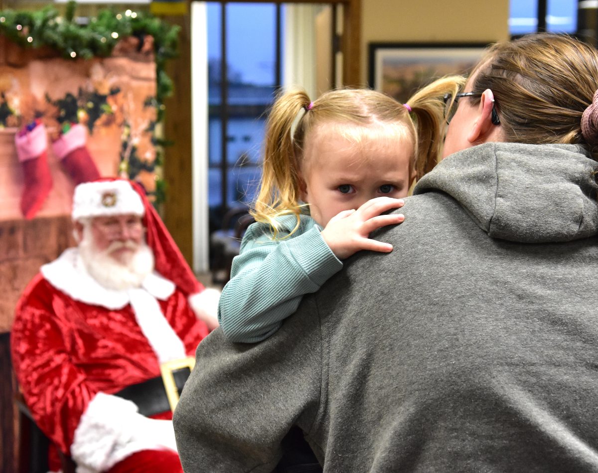 Not everybody was thrilled to see Santa Claus during his recent visits to Solon. Here, Kassidy Miller, all of three years old, sought the safety and comfort of her mom&#8217;s arms rather than face the Jolly Old Elf at the Solon State Bank.