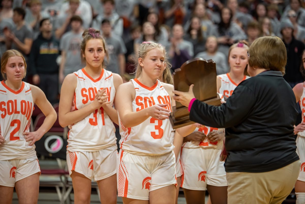 <p>Claire LaDage (3) accepts the Class 3A State Tournament Semifinals trophy after a 46-44 loss to No.7-seeded Sioux Center Thursday, March 2 at Wells Fargo Arena in Des Moines as Addi Greene (2), Gabie Knight (31), Akor Balmer (25), and Kerrigan Lyons look on. It was the first State Tournament appearance for the Lady Spartans since 2006, and the first semifinals appearance since 1998.</p>