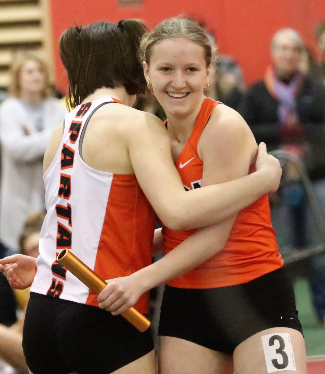 Aisley Foster is embraced by a teammate at the conclusion of the 4x200-meter relay Saturday, March 18 at the WaMaC Indoor meet in Grinnell. Olivia Bonnema, Kerrigan Lyons, Bella Jedlicka, and Foster took fifth in 1:57.72.