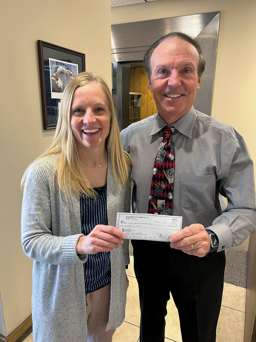 Solon Beef Days Committee treasurer Don C. Ellis presents a check for $1,000 to Coach Emy Williams for the Solon Cross Country Team for the purchase of new timers, watches, and muscle massage therapy equipment.