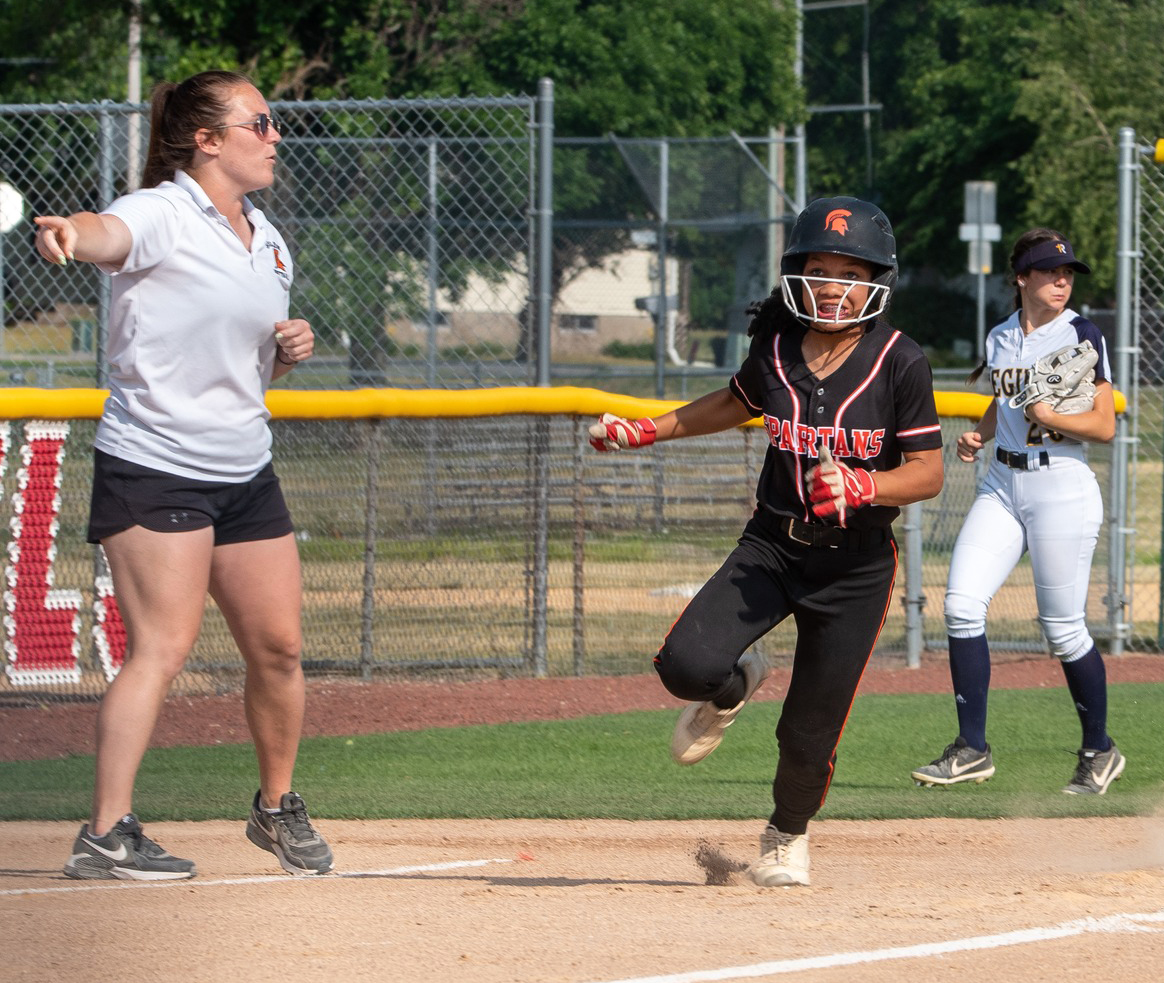 Level 2 Coach Monika Bevans directs Layla Knazze to run for home plate Wednesday, June 14 at home against Regina Catholic.