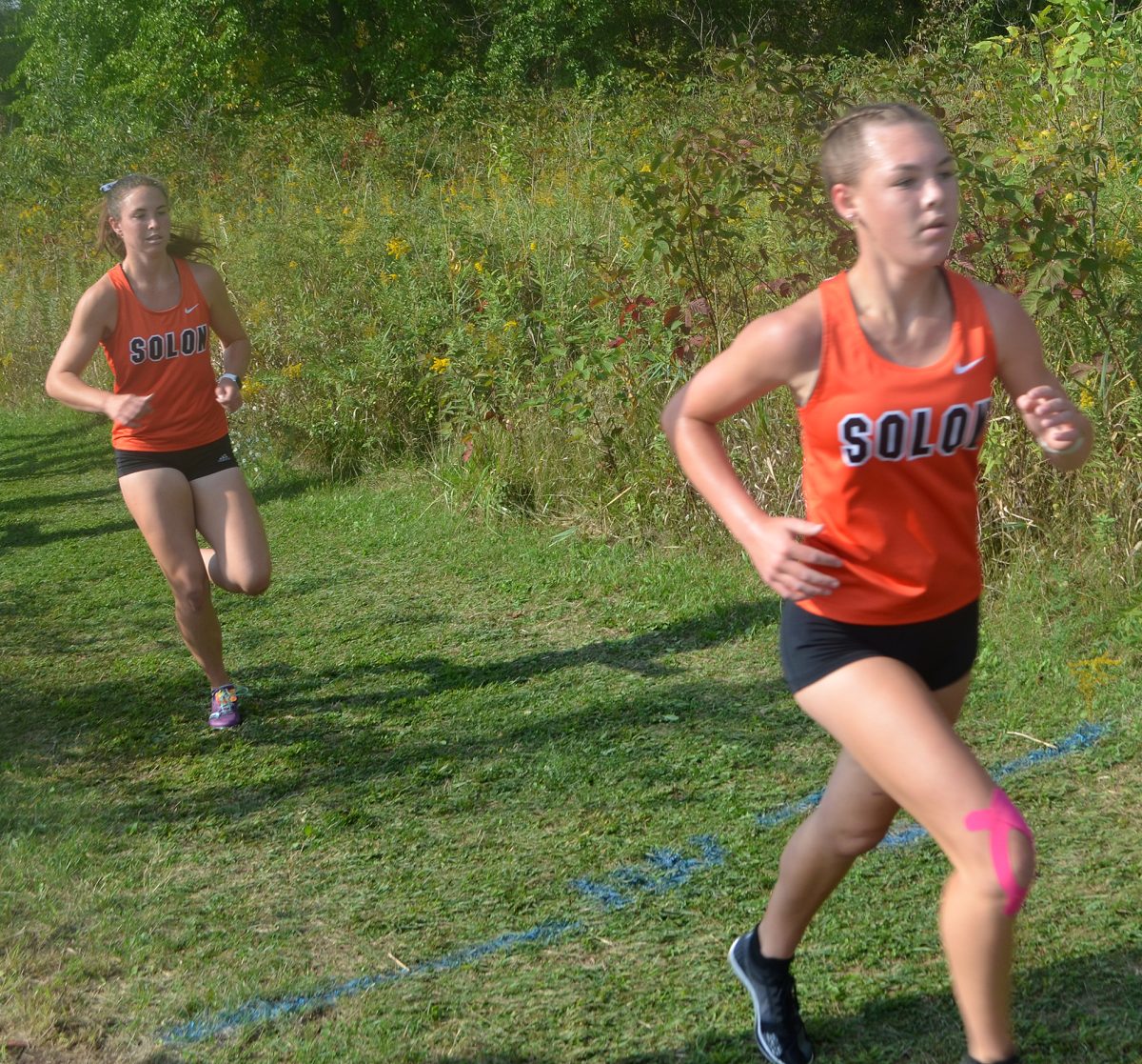 Ava Rolwes (at right) and Gracie Federspiel make their way through overhead prairie grass at the Anamosa Invitational cross country meet, Saturday, Sept. 23. Solon&#8217;s girls are ranked 7th in Class 3A heading into this week.