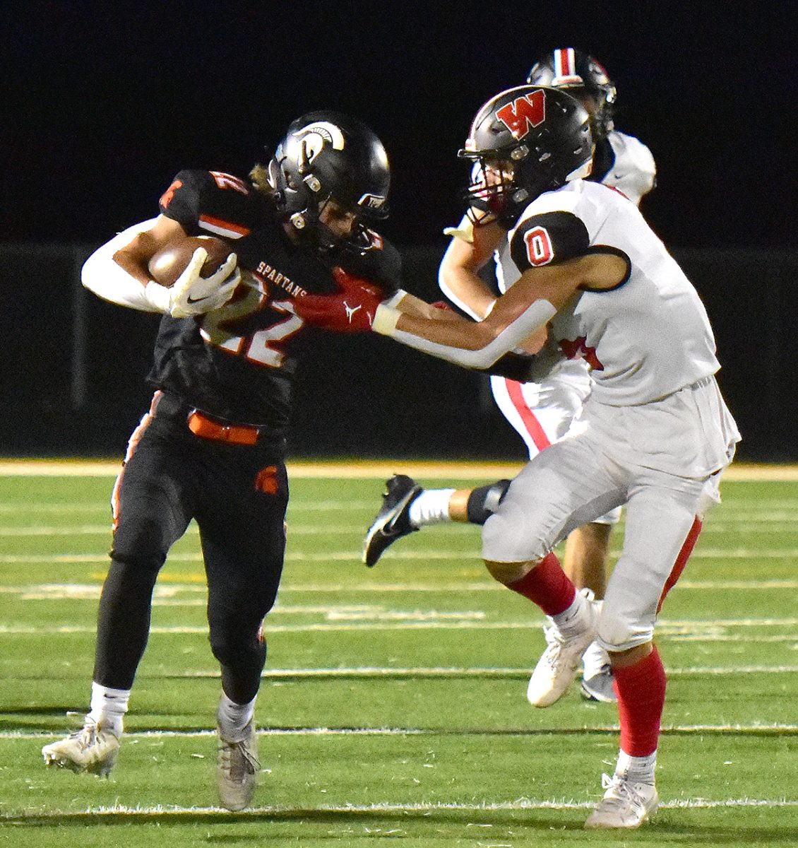 Conlan Poynton (22) tangles with Williamsburg&#8217;s Braylon Wetjen (0) on a carry Friday, October 6 at home. The Spartans dethroned the Raiders from the top of Class 3A District 6 with a 21-14 win.