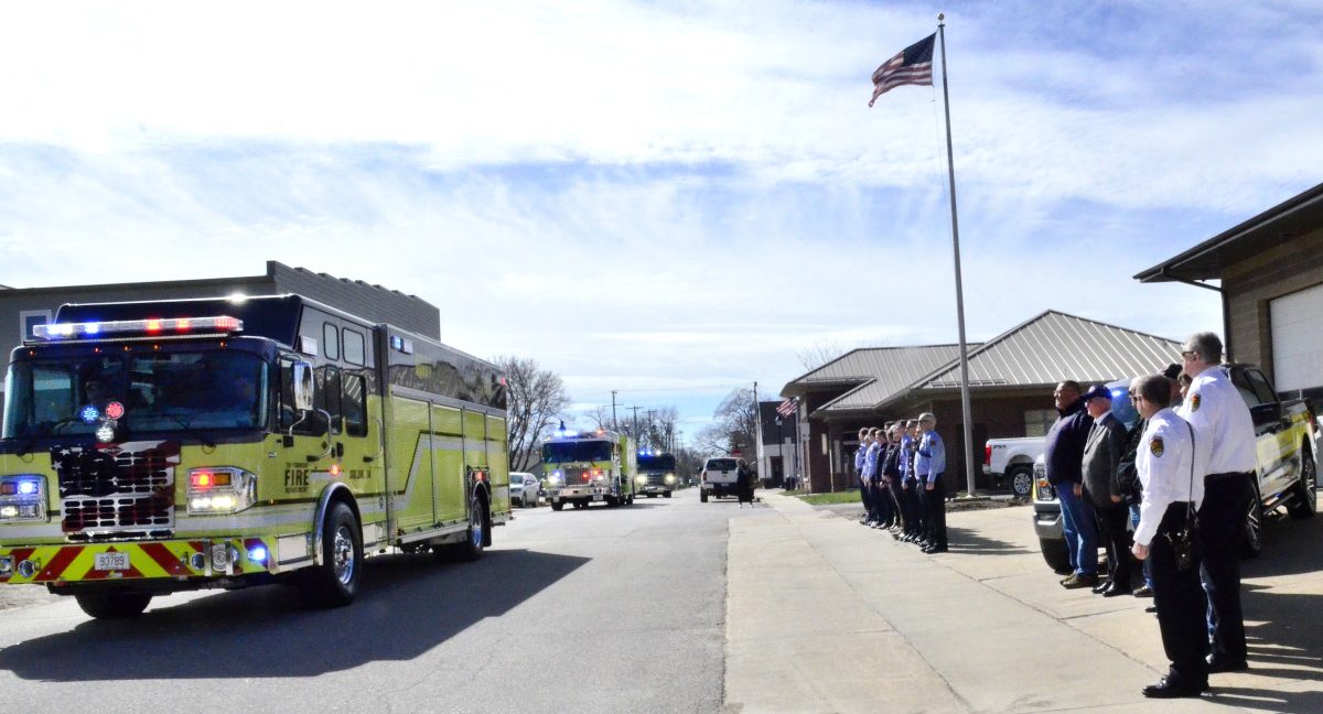 <p>Solon firefighters, current and retired, stand at attention as the procession escorting retired Fire Chief Dan Smith to the Oakland Cemetery passes by the old fire station Saturday morning.</p>