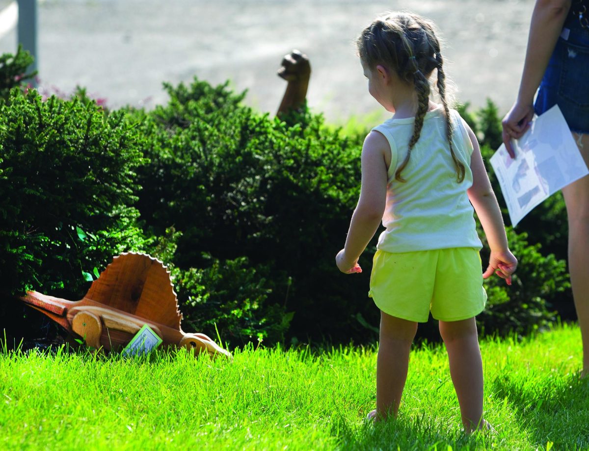 Brodie Hansen looks at one of the dinosaurs that were scattered around the library lawn for the scavenger hunt.