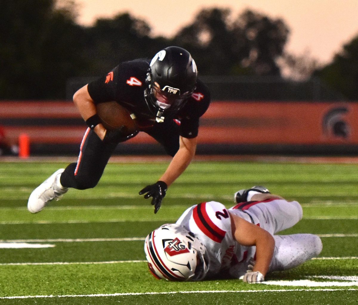 Sophomore Maddox Kelley (4) sails toward the soft new turf after being tripped up by an Assumption defender this past Friday in the varsity season opener. 