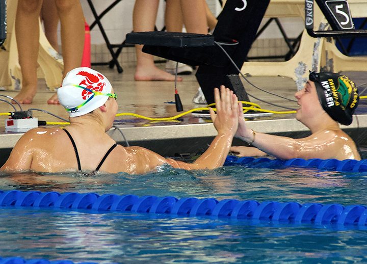 Sophomore Madelyn Elkins high-five’s a Hempstead swimmer after an event during last week’s dual meet between City High and the Mustangs. Elkins joined teammate Grace Hoeper in the winning varsity 4x50 medley and 4x100 freestyle, was 2nd in the 200-IM, and 4th in the 100-freestyle.