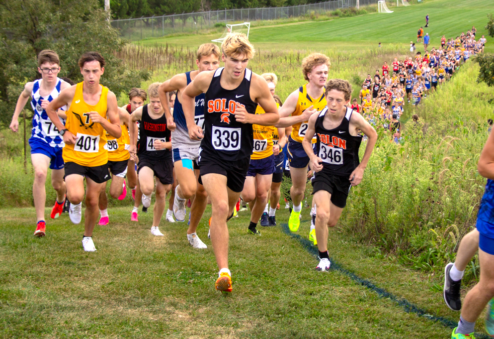 Senior Evan Burg (339) and teammate Anders Holmes, a freshman, charge up the steep hill at the Kickers Soccer park in Iowa City last Thursday during Regina Catholic’s Bob Brown Cross Country Classic.