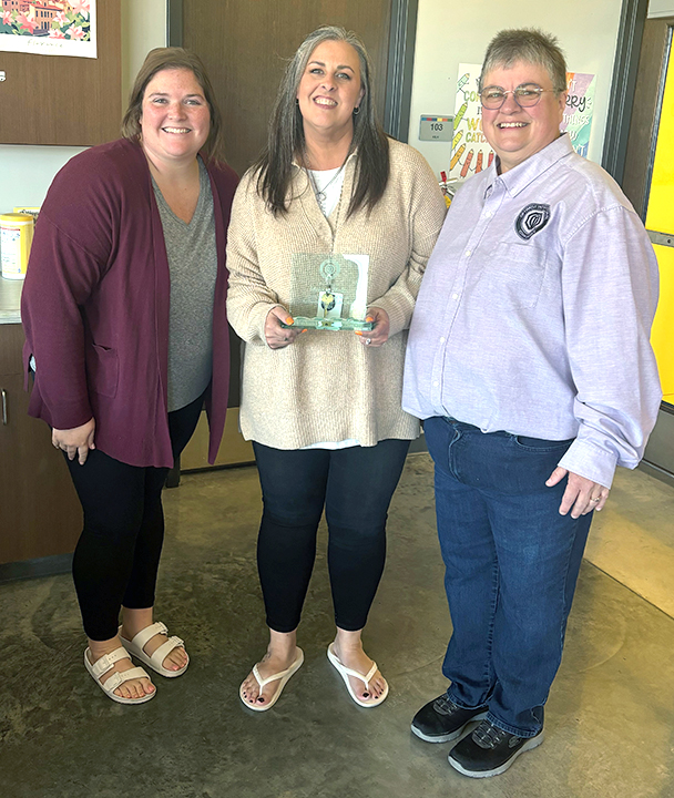 Sami McAtee (left) and Karen McFarland flank Melissa Holtz (SIS Principal) with her Optimist Achievement in Education Award.