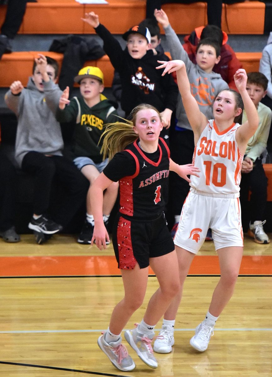 Quinn Armentrout (10) gets a little help with her three-point attempt from some young fans as Assumption’s Gabby Stoffregen (1) watches with concern in Saturday’s Class 3A Region 1 Quarterfinals game in Solon. The Lady Spartans topped the Knights 51-39 to face Mt. Vernon Wednesday, Feb. 19 in the Mustangs’ stable.