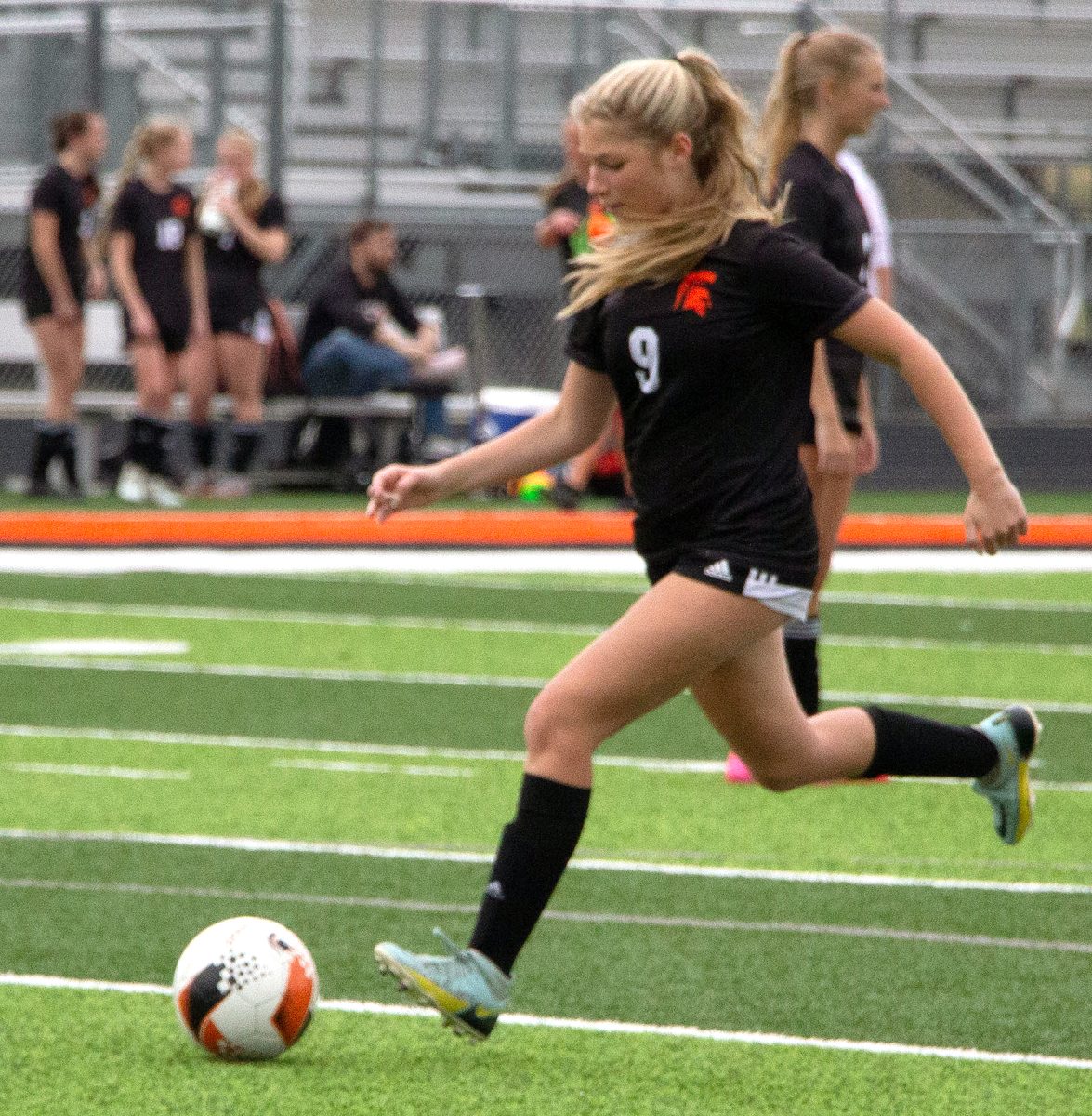Charlotte Leone (9), a senior, takes a practice kick during warm-ups before a scrimmage match against Liberty High School (North Liberty) Thursday, March 27 in Spartan Stadium.