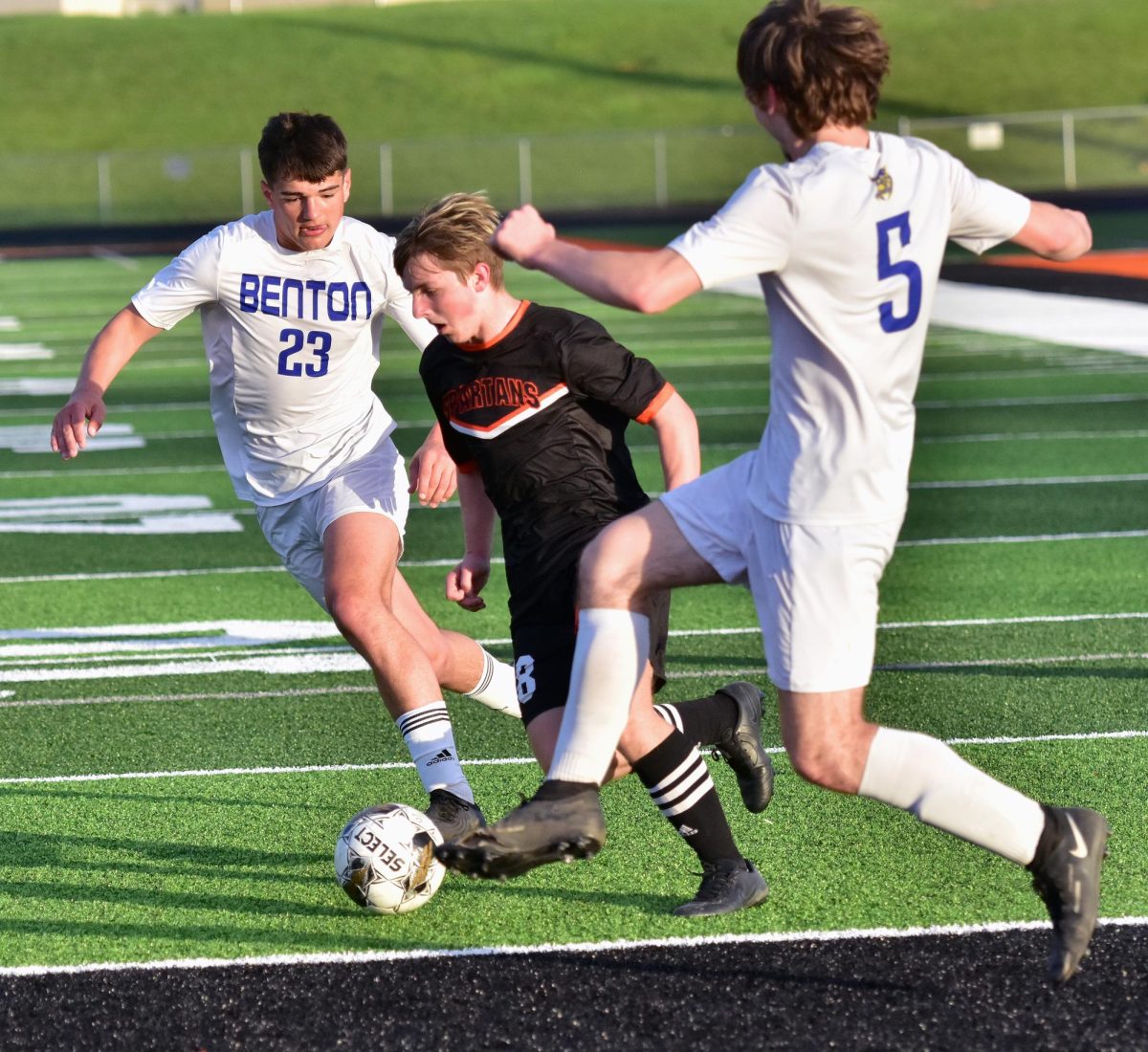 Above: Griffin Spence (18), a freshman, threads the needle between a pair of Bobcat defenders on his way toward the goal Tuesday, April 29 at home.