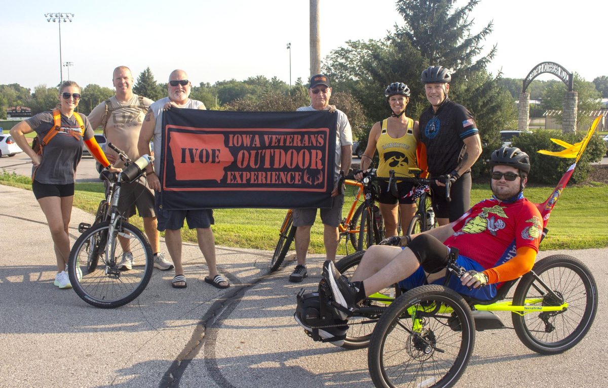 (From left) Lindy and Adam Hopp, Scott Storck (President of IVOE), Denny Hansen, Paula, Nile Heefner, and Gabe Heefner gather together with the IVOE flag before taking off on their ride to Ely Saturday, August 9. The route is part of a new event series started by Gabe and Nile working with the Iowa Veterans Outdoor Experience to support and connect local veterans