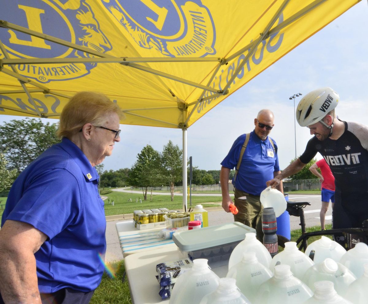 Solon Centennial Lions Club members Marti Hendricks and Jay Proffitt stand ready to assist as Pieter Frolichs refills his water bottle at an aid station the Lions set up at the SRNA Saturday morning in support of the Core 4 bike races.