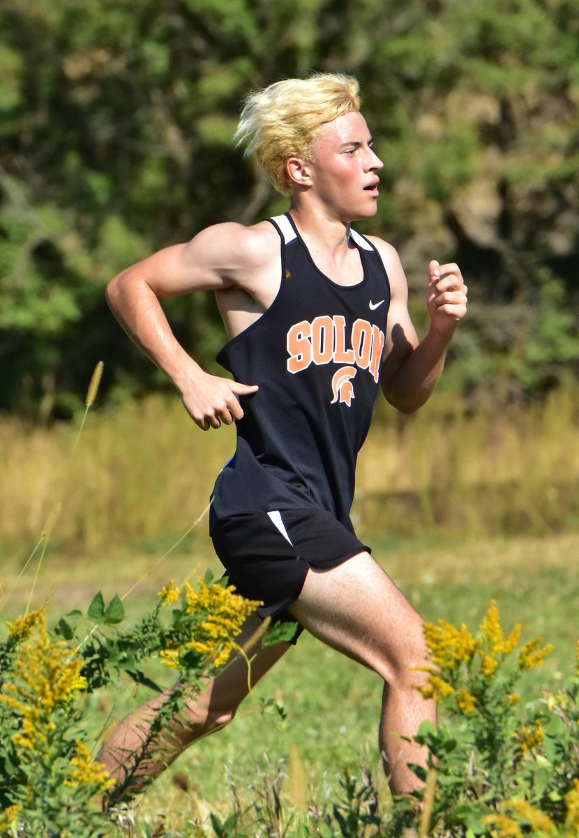 Rene Meza flies past flowering weeds, prairie grass, and content cows in the distance Saturday, Sept. 27 during Anamosa’s invitational meet. Meza was the second Spartan to the finish line with a 14th place showing in 17:54.0.