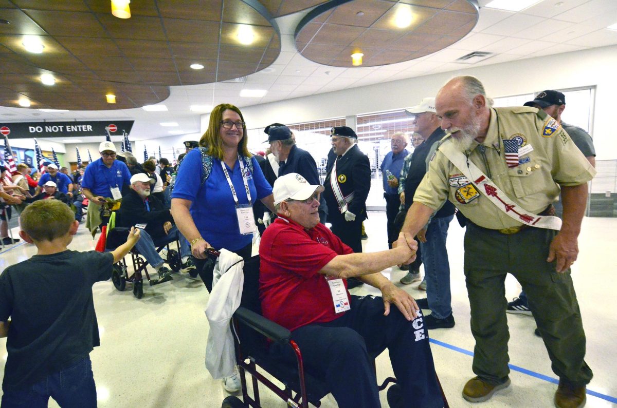 Don Glueck (Scouting BSA, Order of the Arrow) greets Bill Brown as his daughter Lisa (Brown) Popken pushes him through a corridor lined with family, friends, and other well-wishers as the 27th Honor Flight out of the Eastern Iowa Airport in Cedar Rapids comes to an end Tuesday, October 14.