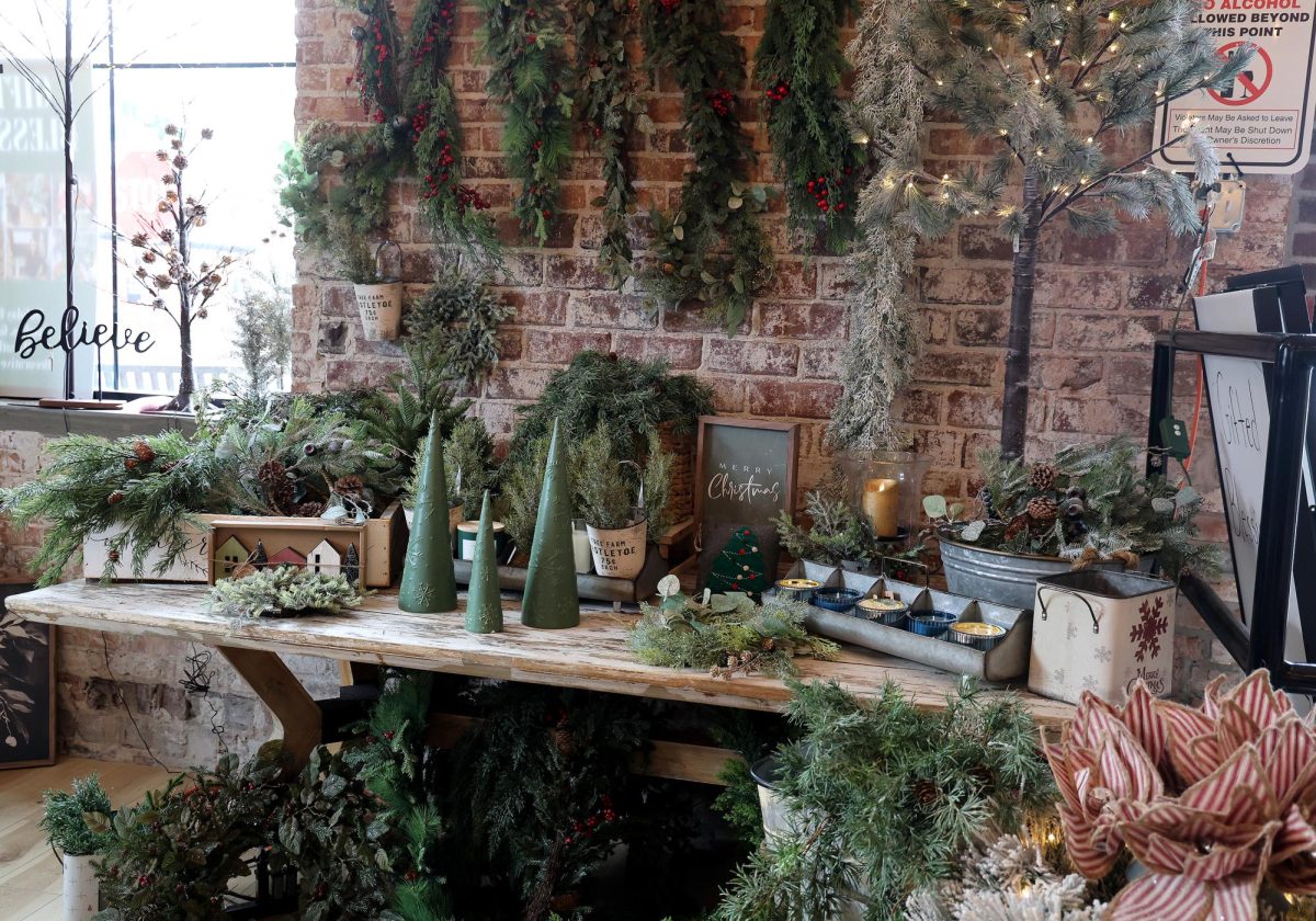 Garlands, greenery, and tabletop trees fill a wooden display at Gifted Blessings, showcasing the shop’s wide range of natural-inspired holiday décor.