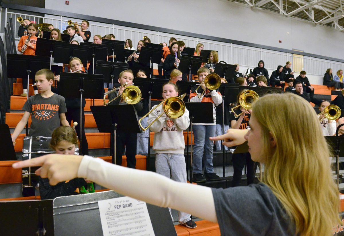 Rachel Ihde directs the 5th grade band as they swing their instruments from left to right while performing Tuesday, Feb. 10 during warm-ups for the varsity girls basketball game.