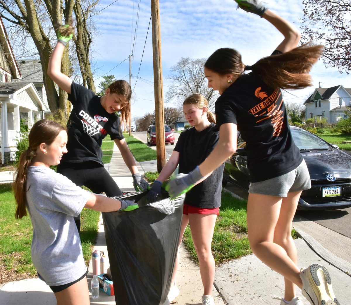 Nora Sanderson, Keatyn Schnoor, Madden Schroeder, and Mailee Schmidt slam dunk leaves into a bag as they do some yard work Tuesday, April 21, during the annual Spartan Day of Service.