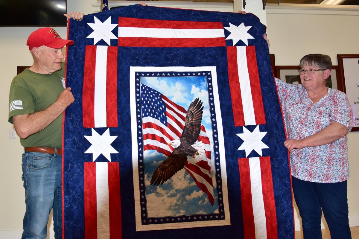Solon veteran Doug Thompson accepts a Quilt of Valor from Pat (at right) and Bill (behind the quilt) Wieland Monday, May 11 at Solon American Legion Stinocher Post 460.