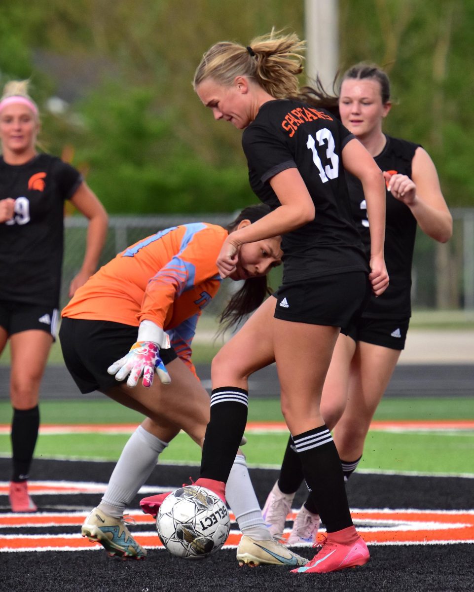 Jillian Janssen (13) taps the ball into South Tama’s goal as Trojan keeper Annaleigh Davenport tries desperately to block her Tuesday, May 12, at home. Janssen, a junior, had one goal in a 10-0 shut-out on Senior Night.