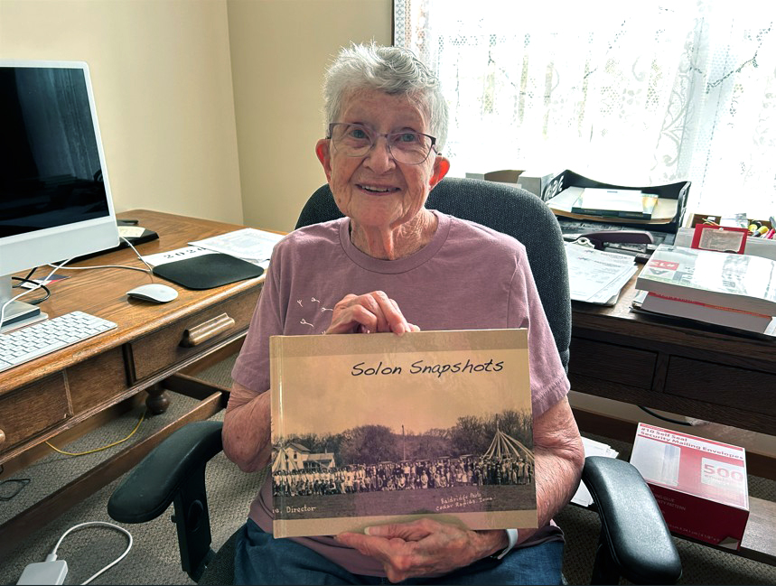 Sandra “Sandy” Hanson poses with the book Solon Snapshots in her home in Solon on April 23.